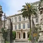 Barberini Palace with ornate gate and palm tree.
