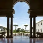 Elegant archway with trees and sculptures outside.